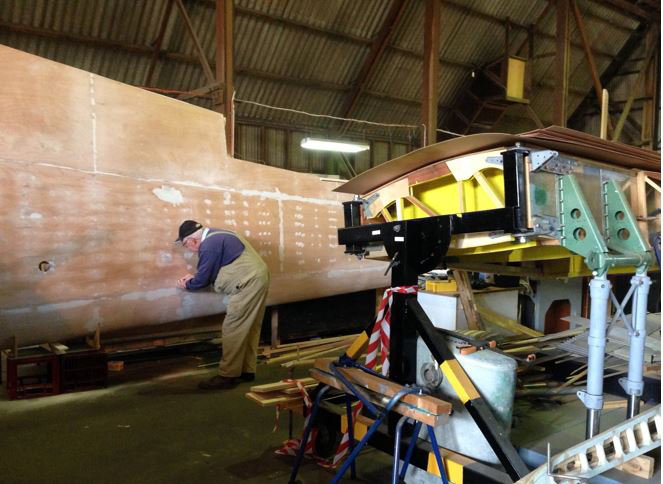 Australian Airspeed Oxford - Project Update 17 Putting the finishing touches on the Oxford's left wing. The aircraft's center section can be seen in its jig on the right side of the frame. (photo via B-24 Liberator Memorial Fund)