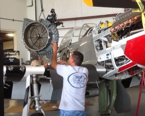 Behind the Scenes, Air Show Performers are Prepped for Action by CAF Dixie Wing 12 Mustang expert, from Vintage V12s in California guides the heavyweight supercharger back to its place. (Image Credit: CAF Dixie Wing)
