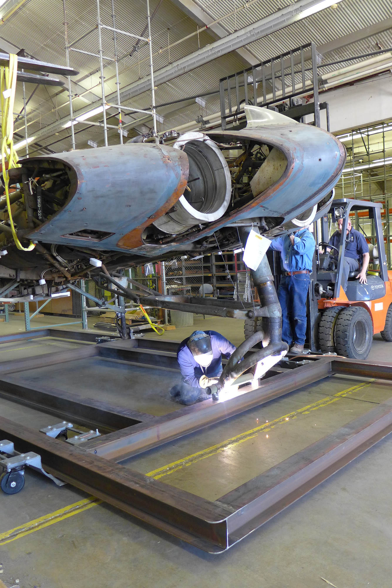 Horten Flying Wing Heading to NASM's Udvar-Hazy Center 14 The Horten's center section is seen suspended in position above the steel transport frame. A contractor is welding a fitting to the cradle which will allow a mounting bolt to firmly attach the nose wheel bogey to the frame. (Lauren Horelick photo via NASM)