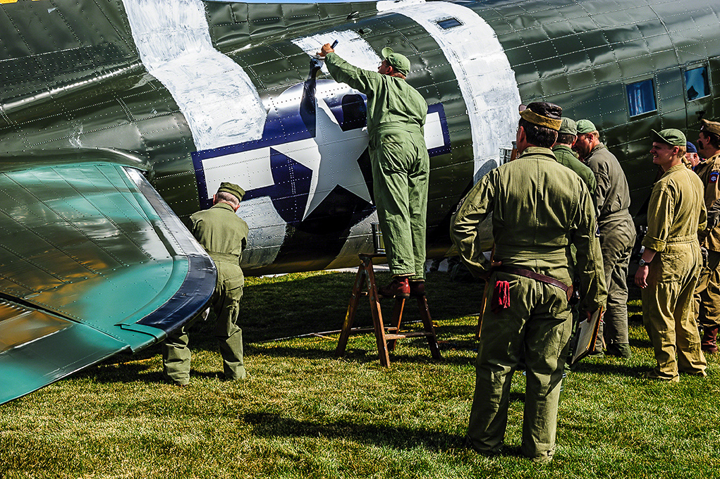 Texas Flying Legends - Oshkosh Here We Come!!! 16 Re-enactors and veterans painting the D-Day stripes on the TFLM C-53 Skytrain at AirVenture 2013 in much the same way as it was done during WWII... with mops and paint brushes. (photo by Jake Peterson)