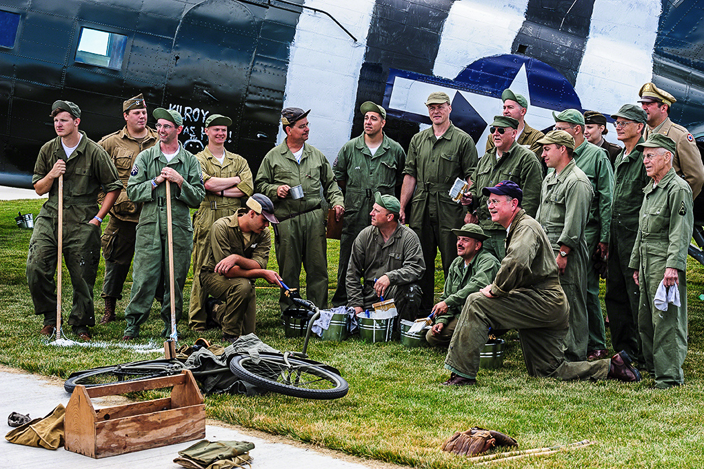 Texas Flying Legends - Oshkosh Here We Come!!! 15 Re-enactors and veterans pose after painting the D-Day stripes on the TFLM C-53 Skytrain at AirVenture 2013. (photo by Jake Peterson)