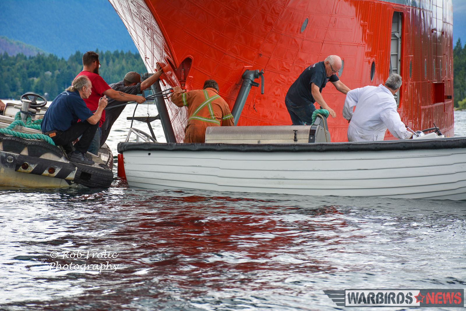 Martin Mars Movements - The Ultimate Flying Experience! 15 Kermit Weeks (far left) on a boat beneath the giant hull of Hawaii Mars on Sproat Lake. (photo by Rob Frolic)