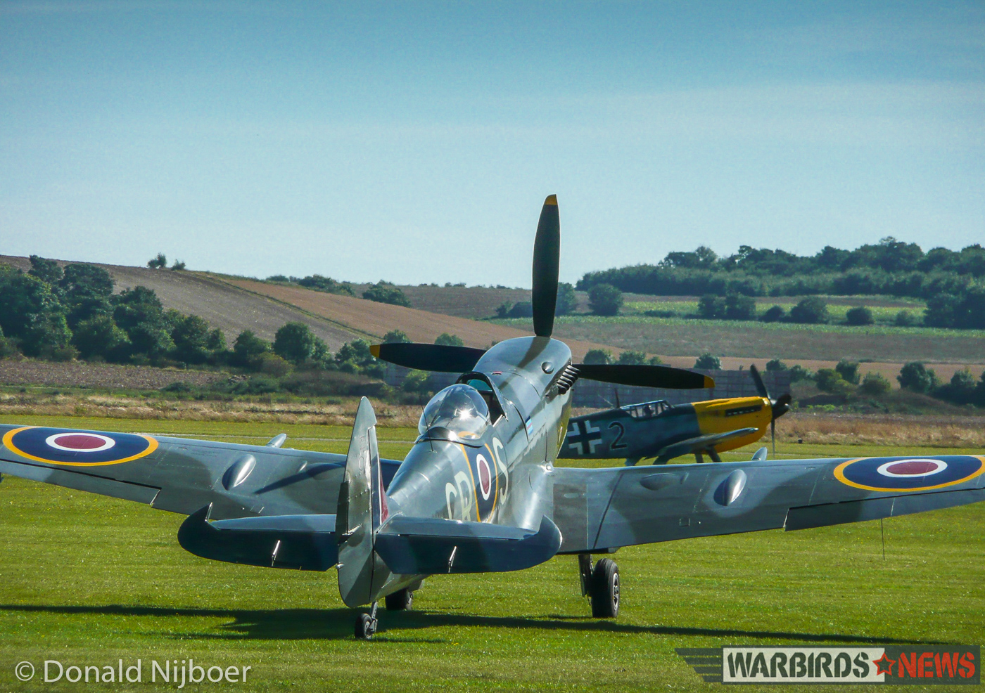 Duxford - Meet the Fighter Air Show 13 Supermarine Spitfire Mk.XVI TD248 sits on the grass at Duxford while a Hispano Buchon dummied up to represent a Messerschmitt Bf 109 taxies by in the background. (photo by Donald Nijboer)