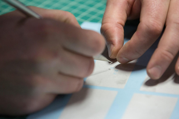 Texas Flying Legends P-51C Restoration Report 35 Close in you can see how exacting this work can be when creatings small lines of print labels. Max is removing the vinyl from the area of a tiny letter. (photo via AirCorps Aviation)