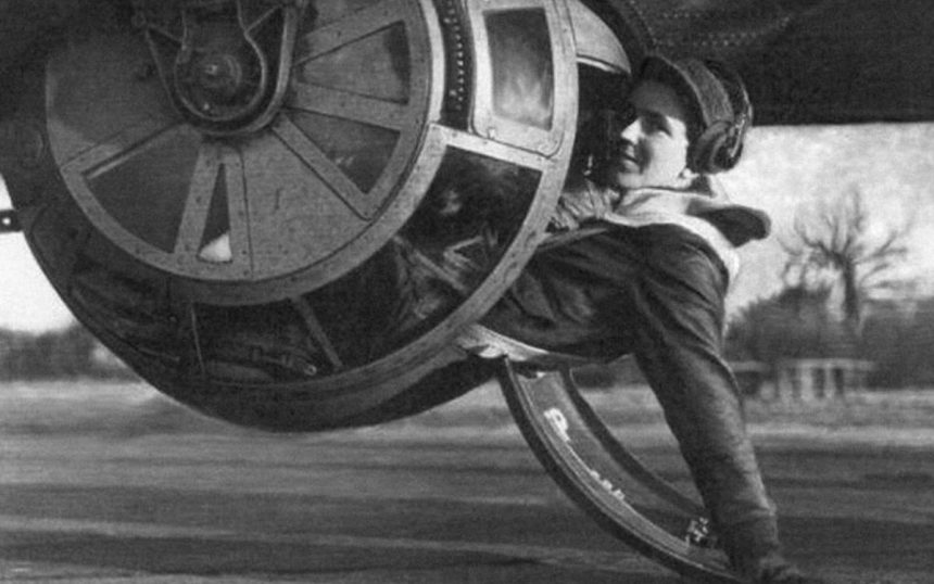 S Sgt. Alan E. Magee poses for the camera halfway into the tight confines of the ball turret of a B 17 Flying Fortress